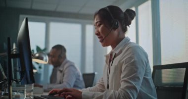 Çağrı merkezi: Müşteri ile iletişim kurma, bilgisayar kullanma, çevrimiçi müşteri hizmetleri sağlama konularında Asya 'nın dost canlısı teknik destek uzmanının yan görüntüsü. Çeşitli yardım hattı operatörlerinden oluşan takım.