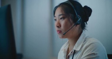 Psikolojik yardım hattının modern çağrı merkezi: Asyalı kadın yardım hattının portresi kulaklıkla konuşuluyor, online danışmanlık yapılıyor, zihinsel sağlık yardımı yapılıyor. Duygusal destek.