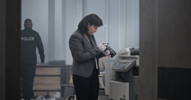 Ofis soygunu ya da cinayet, olay yerinde çalışan soruşturma ekibi. Kadın kriminalist kanıt fotoğrafları çekiyor. Afrikalı Amerikalı polis parmak izi arıyor, dedektif odaya giriyor..