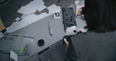 Hırsızlık ya da cinayet davası: Profesyonel kamerayla bıçak çeken kadın kriminalist. Numaralı işaret, cinayet silahı kanıtının yanında duruyor. Adli tıp uzmanı olay yerinde çalışıyor.