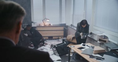 Ofis soygunu, dedektifin olay yerini incelemesi. Kadın kriminalist ipuçlarının fotoğrafını çeker, Afro-Amerikan polisi parmak izi arar. Suç araştırma ekibi. Doli Vuruşu.