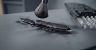 Ofis soygunu ya da cinayet davası: Adli tıp uzmanı ya da kriminalist, cinayet silahında fırça ve manyetik toz kullanarak parmak izi arıyor. Suç mahallinde soruşturma.