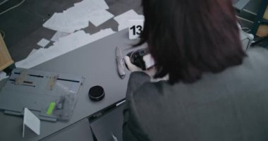 Hırsızlık ya da cinayet davası: Profesyonel kamerayla bıçak çeken kadın kriminalist. Numaralı işaret, cinayet silahı kanıtının yanında duruyor. Adli tıp uzmanı olay yerinde çalışıyor.