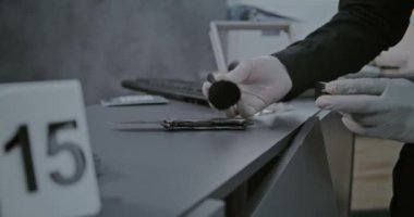 Cinayet ya da soygun vakası, kriminalist ya da adli tıp uzmanının cinayet silahında fırça ve manyetik toz ile parmak izi bulması. Numaralı işaretleyici olay yeri kanıtlarının yanında duruyor..