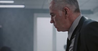 Ofis soygunu ya da cinayet davası, takım elbiseli erkek dedektifin olay yerindeki kanıtları incelemesi. Adli tıp uzmanı arka planda parmak izi arıyor. Suç araştırma ekibi çalışıyor.