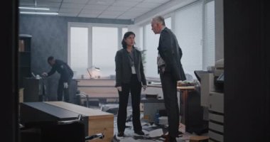 Ofis soygunu davası: suç araştırma ekibi çalışıyor. Erkek dedektif olay yerini inceleyen kadın adli tıp uzmanıyla konuşuyor. Afrikalı Amerikalı polis parmak izi arıyor. Kolluk kuvvetleri.