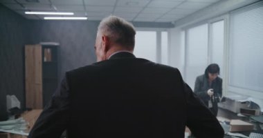 Ofis soygunu davası, takım elbiseli erkek dedektifin olay yerini incelemesi. Kadın adli tıp uzmanı ipuçlarının ve kanıtların fotoğraflarını çekiyor, Afro-Amerikan polis memuru parmak izlerini araştırıyor..