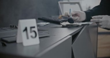 Soygun ya da cinayet davası: Numaralı işaretleyici olay yeri kanıtlarının yanında duruyor. Cinayet silahında manyetik toz kullanarak parmak izi taraması yapan kriminalist ya da adli tıp uzmanına odaklanın..