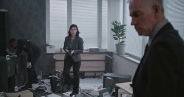 Ofis soygunu, olay yerinde olay yeri inceleme ekibi. Kadın kriminalist ipuçlarının ve kanıtların fotoğraflarını çeker, sonra da erkek dedektifle konuşur. Arka planda Afro-Amerikan polisi çalışıyor..