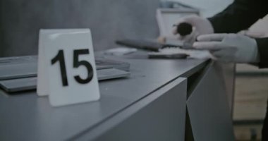 Soygun ya da cinayet davası: Numaralı işaretleyici olay yeri kanıtlarının yanında duruyor. Cinayet silahında manyetik toz kullanarak parmak izi taraması yapan kriminalist ya da adli tıp uzmanına yakın durun..