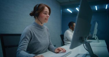 Gece Çağrı Merkezi Ofisi: Kulaklık izleme konusunda ciddi kadın teknik destek uzmanı, PC üzerinden verileri, çağrı yoluyla çevrimiçi müşteri destek hizmeti sunar. Çoklu etnik yardım hattı operatörleri ekibi çalışıyor.