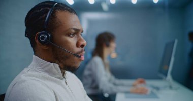 Çağrı merkezi: Afrika kökenli Amerikalı teknik destek uzmanının portresi, çağrı üzerine danışmanlık yapan müşteriye çevrimiçi müşteri hizmeti sunuyor. Yardım hattı operatörlerinden oluşan ekip çalışıyor. E-ticaret.