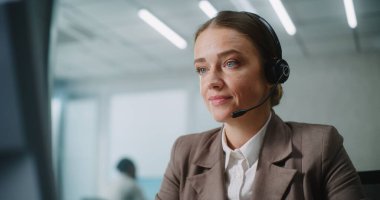 Beyaz kadın modern ofiste çalışıyor: Kadın teknik destek operatörü veya müşteri yöneticisi kulaklıkla müşteriyle konuşuyor, bilgisayar kullanıyor, çevrimiçi müşteri hizmetleri sağlıyor. E-ticaret ve E-ticaret.