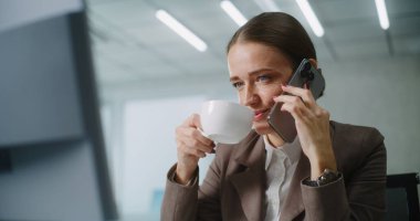 Pozitif kadın pazarlama uzmanı ya da E-ticaret müdürü iş ortağıyla konuşur, cep telefonuyla müşteriye danışır, bilgisayar kullanır. Kafkasyalı iş kadını modern ofiste çalışıyor. E-iş.