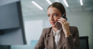 Kafkasyalı iş kadını, müşterisiyle ya da iş ortağıyla cep telefonu kullanarak agresif bir şekilde konuşur, bilgisayar ekranına bakar. Modern ofiste pazarlama müdürü veya finans uzmanı olarak çalışıyor. E-ticaret.