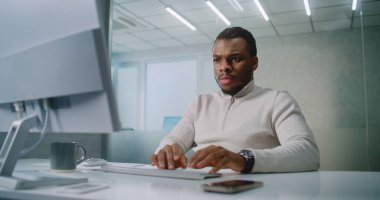 Modern ofis: Kafası karışmış Afrikalı Amerikalı pazarlama uzmanı veya E-ticaret yöneticisi iş ortağı veya müşterisiyle bilgisayar kullanarak iletişim kuruyor. Genç işadamına kötü haberler geliyor. E-iş konsepti