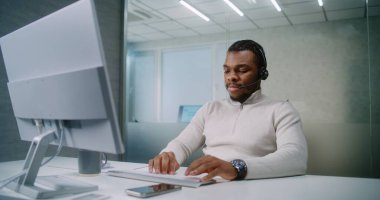 Kulaklık danışmanlığındaki Afrikalı Amerikalı teknik destek operatörü ya da müşteri yöneticisi müşteri ya da iş ortağı bilgisayar kullanır. Başarılı pazarlama uzmanı parlak modern ofiste çalışıyor. E-ticaret