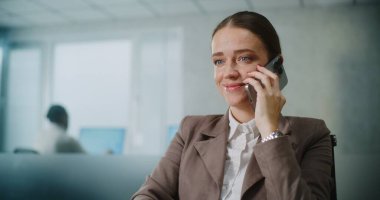 Beyaz iş kadını iş ortağıyla konuşuyor ya da cep telefonuyla müşteriye danışıyor, bilgisayar kullanarak verileri izliyor, kahve içiyor. Kadın pazarlama uzmanı parlak modern ofiste çalışıyor. E-ticaret