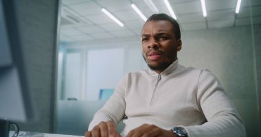 Modern ofis: Kafası karışmış Afrikalı Amerikalı pazarlama uzmanı veya E-ticaret yöneticisi iş ortağı veya müşterisiyle bilgisayar kullanarak iletişim kuruyor. Genç işadamına kötü haberler geliyor. E-iş konsepti