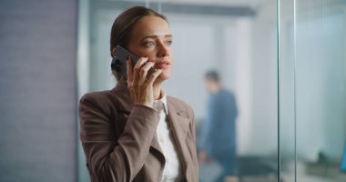 Kafkasyalı başarılı iş kadını iş stratejisini ortağıyla tartışıyor ya da cep telefonuyla müşterisine danışıyor. E-ticaret şirketinin modern ve donanımlı ofisinde çalışan kadın pazarlama uzmanı..