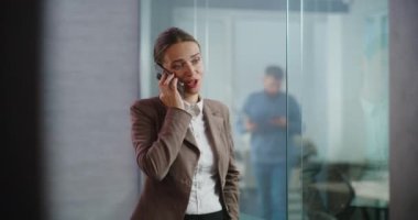 Kafkasyalı başarılı iş kadını cep telefonuyla iş anlaşması hakkında konuşuyor, yeni proje veya şirket stratejisini partneriyle tartışıyor. Kadın pazarlama uzmanı donanımlı E-ticaret ofisinde çalışıyor..