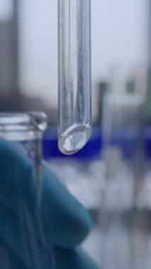 Kimyagerin cam şişeye huni dökerek sıvıyı akıttığı ileri düzey tıp laboratuvarı. Profesyonel bilim adamı laboratuvar ekipmanları kullanarak kimyasal deney yapıyor. Kimya.