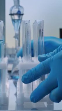 Gelişmiş tıbbi araştırma laboratuvarı: Eldiven giyen profesyonel bilim adamı pipet kullanıyor, analiz için test tüplerine cam şişeden sıvı döküyor. Bilimsel Laboratuvarda çalışıyorum. Uyuşturucu geliştirme. Kapat..