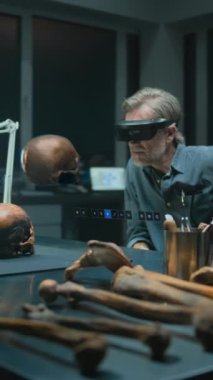 VR kulaklıklı dikey çekim arkeoloğu, fosil kafatası kullanarak eski insan anatomisini araştırıyor. Tarama yazılımının kullanıcı arayüzü ile üç boyutlu görüntüleme.