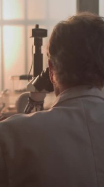 Olgun kimyager ya da mikrobiyolog fosil örneğini mikroskop altında analiz eder. Bilim adamı veya arkeolog ileri arkeoloji laboratuvarında profesyonel ekipmanlarla çalışıyor. Dikey çekim