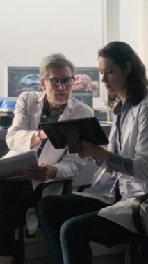 Laboratuvar önlüklü erkek ve kadın bilim adamları bilimsel araştırmalar yapıyorlar, tablet bilgisayar kullanıyorlar ve tartışıyorlar. Paleontologlar veya arkeologlar ileri arkeoloji laboratuvarında çalışırlar. Bilim konsepti.