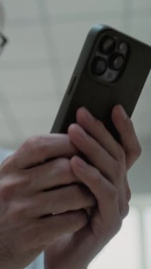 Laboratuvar önlüğü giymiş yetişkin bir bilim adamının sohbet ederken, internette veya cep telefonuyla sosyal medyada sörf yaparken yakın plan çekimleri. Modern arkeoloji laboratuvarı. Dikey