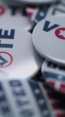 Üzerinde Amerikan bayrağı logosu ve yazıtları olan vatansever rozetlerin dikey çekimi. Amerika Birleşik Devletleri 'nde başkanlık seçimleri. Siyasi ırk ve seçim haberleri. Demokrasi ve vatanseverlik