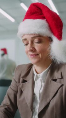 Beyaz, Noel Baba şapkalı başarılı iş kadını klavyede veri daktilo ediyor, bilgisayar kullanıyor. Modern iş ofisinde kadın pazarlama uzmanı Noel süslemeleri yapıyor. E-ticaret.
