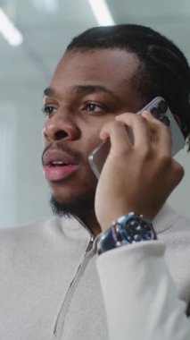 Afrikalı Amerikalı pazarlama uzmanı ya da E-ticaret müdürü iş ortağıyla anlaşma hakkında konuşur, cep telefonundaki müşteriye danışır. Genç iş adamı parlak modern ofiste çalışır. E-iş konsepti.