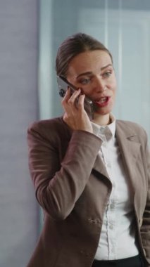 Dikey çekim başarılı iş kadını iş anlaşması hakkında cep telefonuyla konuşuyor, yeni proje veya şirket stratejisini partneriyle tartışıyor. Kadın pazarlama uzmanı, donanımlı E-ticaret alanında çalışıyor.