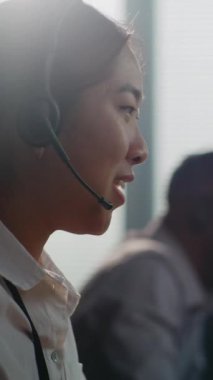 Asyalı yardım hattı operatörünün telefon görüşmelerini dikey çekimleri müşteriye çevrimiçi yardım sağlıyor. Modern çağrı merkezinde çeşitli teknik müşteri destek uzmanları çalışıyor.