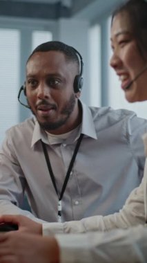 Dikey olarak iki çoklu etnik yardım hattı operatörü iş görüşmeleri yapıyor, bilgisayarla görüşme yapıyor. Çevrimiçi müşteri desteğinde çalışan teknik destek uzmanları.