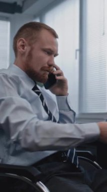 Analizci, satış departmanının sonuçlarını cep telefonuyla raporlayarak ve tartışarak kağıtları inceliyor. Bilgisayar ekranında gösterilen finansal göstergeler ve diyagramlar. Dikey