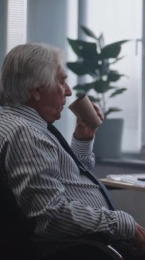 Dikey çekim Yorgun kıdemli finans çalışanı kahve içer, kağıtları ve belgeleri analiz eder, erkek arkadaşla konuşur. PC ekranında sermaye piyasası ve hisse senetleri görülüyor. Uluslararası borsa şirketi.