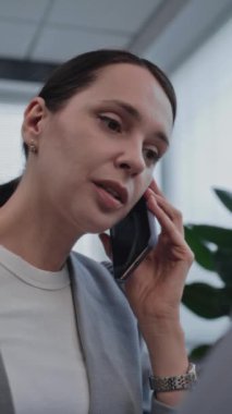 Uluslararası borsa şirketinde çalışan güzel bir genç kadının dikey çekimi. Kadın borsacı cep telefonuyla hisse senedi almak için müşteriyle konuşuyor. Ticaret ve iş konsepti.