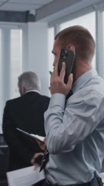 Uluslararası borsa şirketinin modern ofisinde çalışmak: Finansal danışman, yatırımcı müşteriye yatırım hakkında danışmanlık yapan, telefonla konuşan. Gergin kıdemli patron görüşmeleri kontrol ediyor..