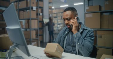 Posta servisi deposu veya E-ticaret mağazası: Afro-Amerikan lojistik koordinatörü telefonla konuşur, paketleri kontrol eder, bilgisayar kullanır. Sıralama merkezi çalışanı karton kutularla çalışır.