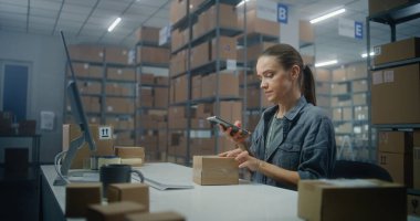 Kadın lojistik müdürü paketleri akıllı telefondan tarıyor, bilgisayardan bilgi giriyor, postanede çalışıyor. Merkez çalışanı nakliye için kutulara bakıyor. E-ticaret çevrimiçi sipariş