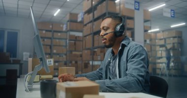 Afro-Amerikan lojistik koordinatörü, telefonda müşteriyle kulaklık sohbeti yapıyor, bilgisayar kullanıyor, posta servisinde ya da E-ticaret deposunda çalışıyor. Merkez çalışanı karton kutuları kontrol ediyor.