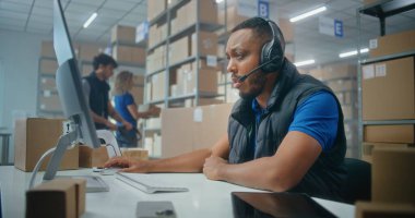 Afro-Amerikan lojistik koordinatörü, telefonda müşteriyle kulaklık sohbeti yapıyor, bilgisayar kullanıyor, postanede ya da e-ticaret deposunda çalışıyor. Karton kutular taşıyan tasnif merkezi çalışanları.