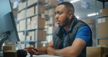 Afrikalı Amerikalı postane çalışanı karton paketleri barkod tarayıcı kullanarak tarıyor, bilgisayarla çalışıyor. Teslimat için kutuları müşterilere taşıyan tasnif merkezi çalışanları. Çevrimiçi E-ticaret mağazası deposu.