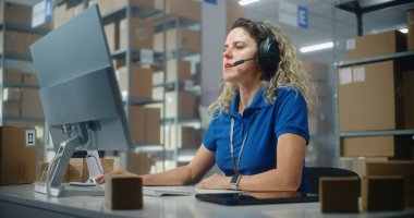 Female customer support specialist in logistics in headset talks to client, uses computer, works in postal service or online store storage. Warehouse employees checking cardboard boxes for delivery. clipart