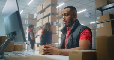 Afrikalı Amerikalı postane çalışanı karton paketleri barkod tarayıcı kullanarak tarıyor, bilgisayarla çalışıyor. Teslimat için kutuları müşterilere taşıyan tasnif merkezi çalışanları. Çevrimiçi mağaza. Yavaş çekim