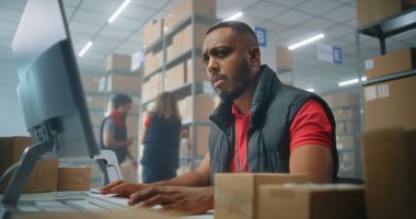 Afrikalı Amerikalı postane çalışanı karton paketleri barkod tarayıcı kullanarak tarıyor, bilgisayarla çalışıyor. Teslimat için kutuları müşterilere taşıyan tasnif merkezi çalışanları. Çevrimiçi mağaza. Yavaş çekim