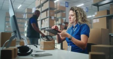 Kadın depo görevlisi, müşterilere gönderilecek paketleri hazırlamak için tablet bilgisayar kullanarak paketleri tarıyor. Karton kutular taşıyan tasnif merkezi çalışanları. Postane veya çevrimiçi mağaza deposu.